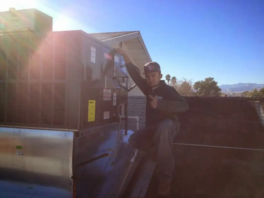 HVAC technician performing Air Duct Cleaning on a rooftop unit in Kirkwood